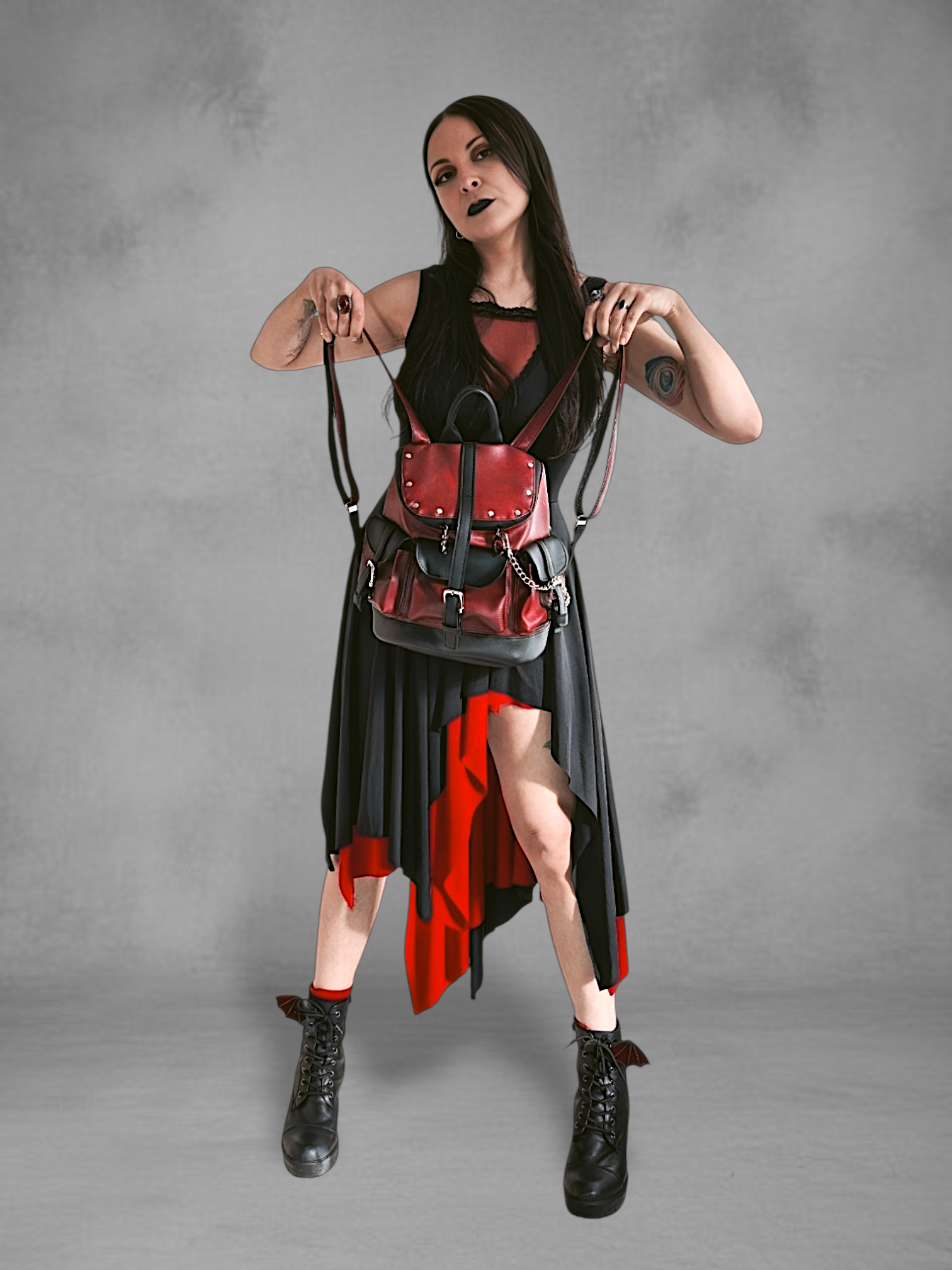 Mochila gotica de cuerina rojo borgona y negro en las manos de una modelo