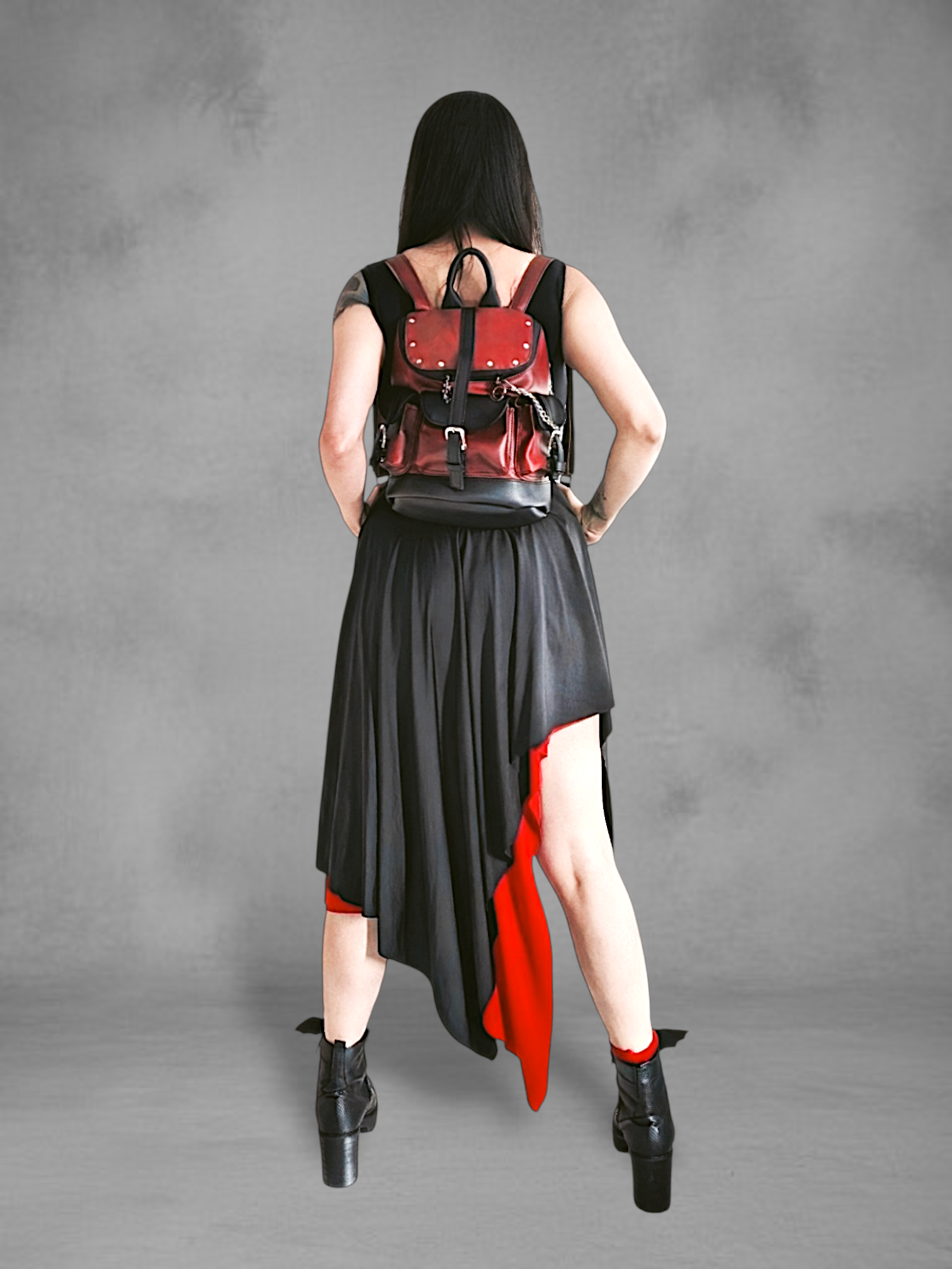 Mochila gotica de cuerina rojo borgona y negro en las manos de una modelo
