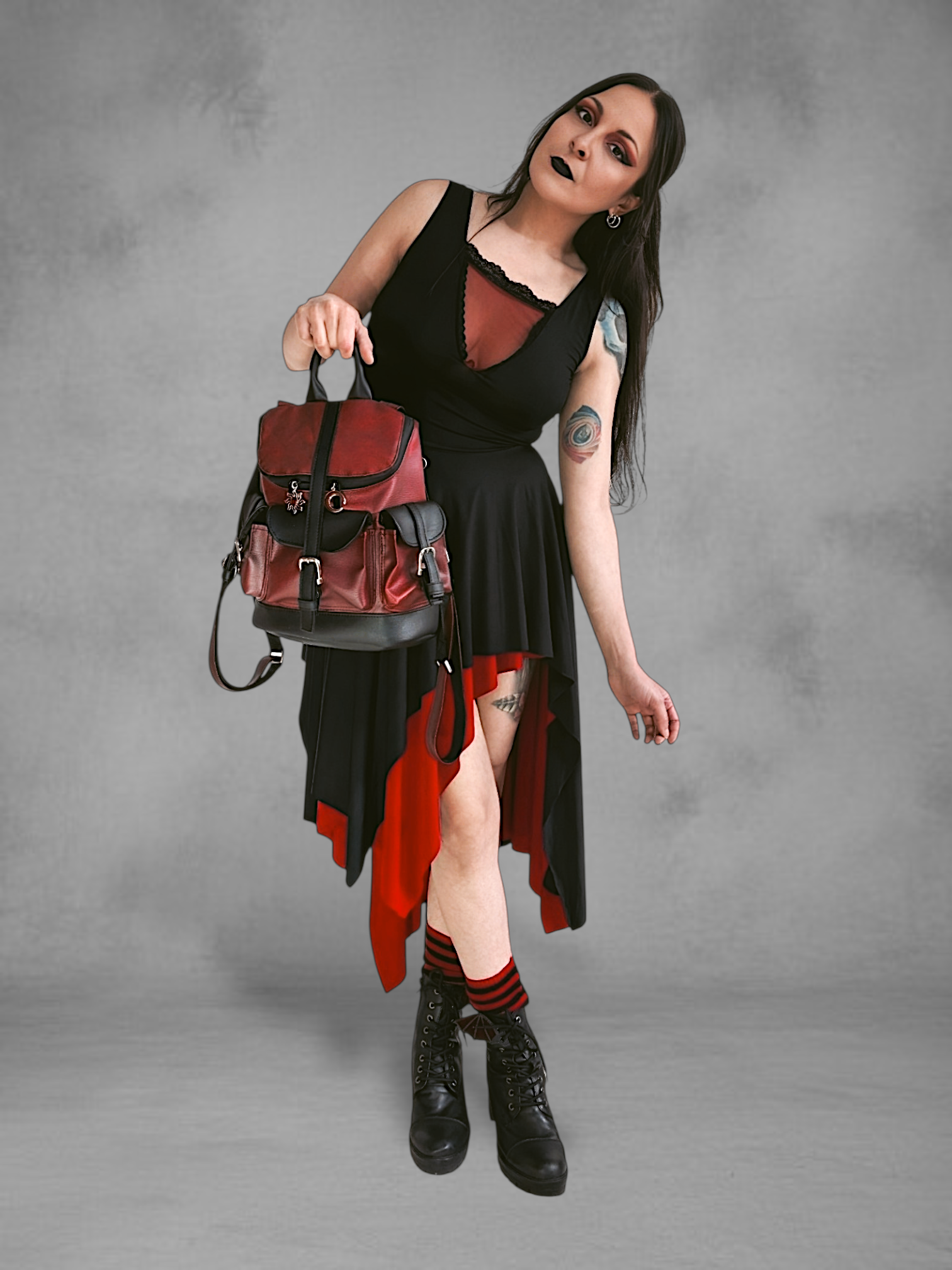 Mochila gotica de cuerina rojo borgona y negro en las manos de una modelo