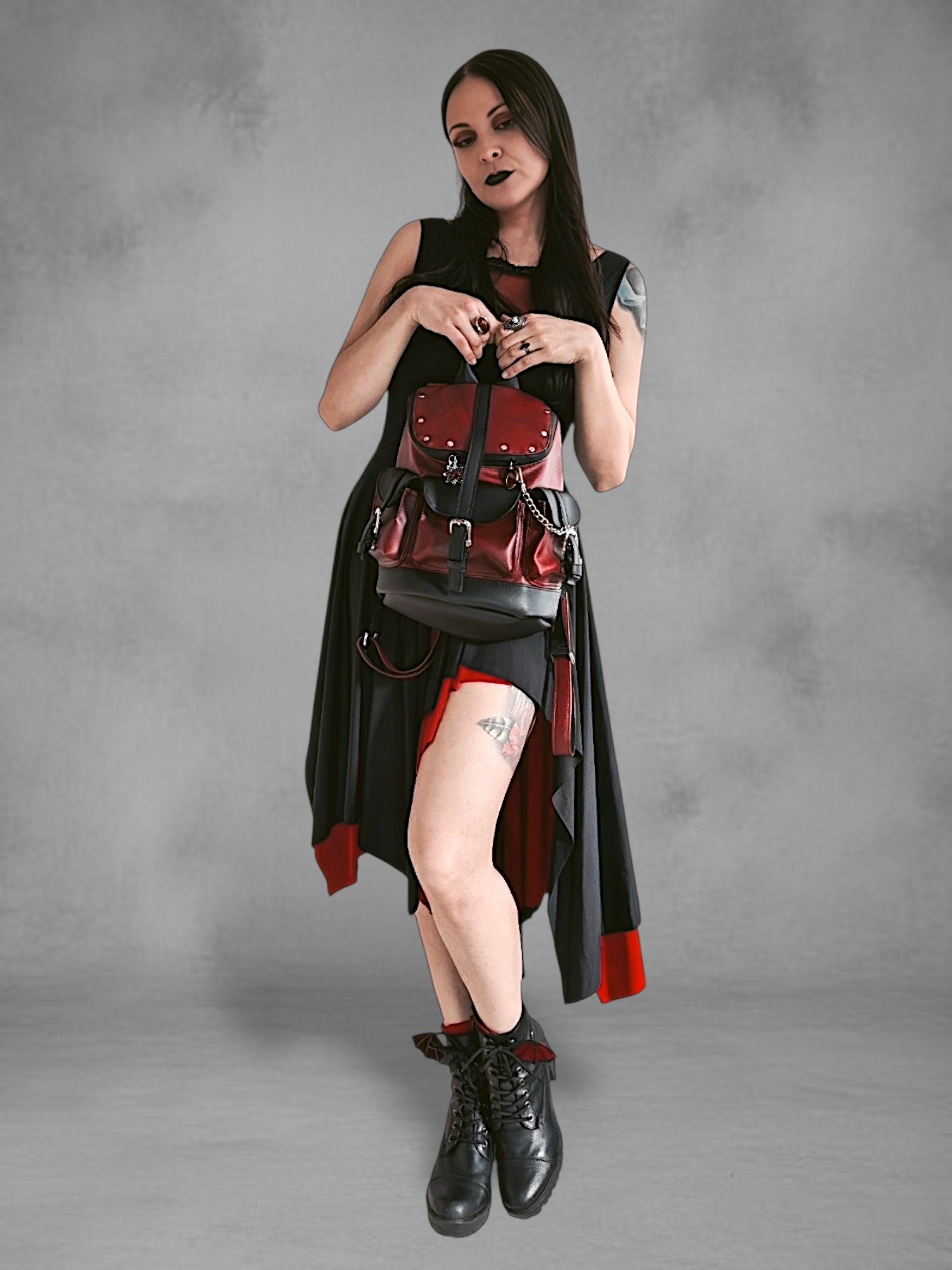 Mochila gotica de cuerina rojo borgona y negro en las manos de una modelo