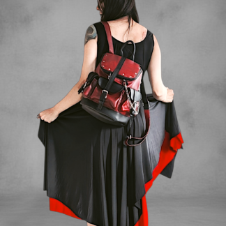 Mochila gotica de cuerina rojo borgona y negro en las manos de una modelo