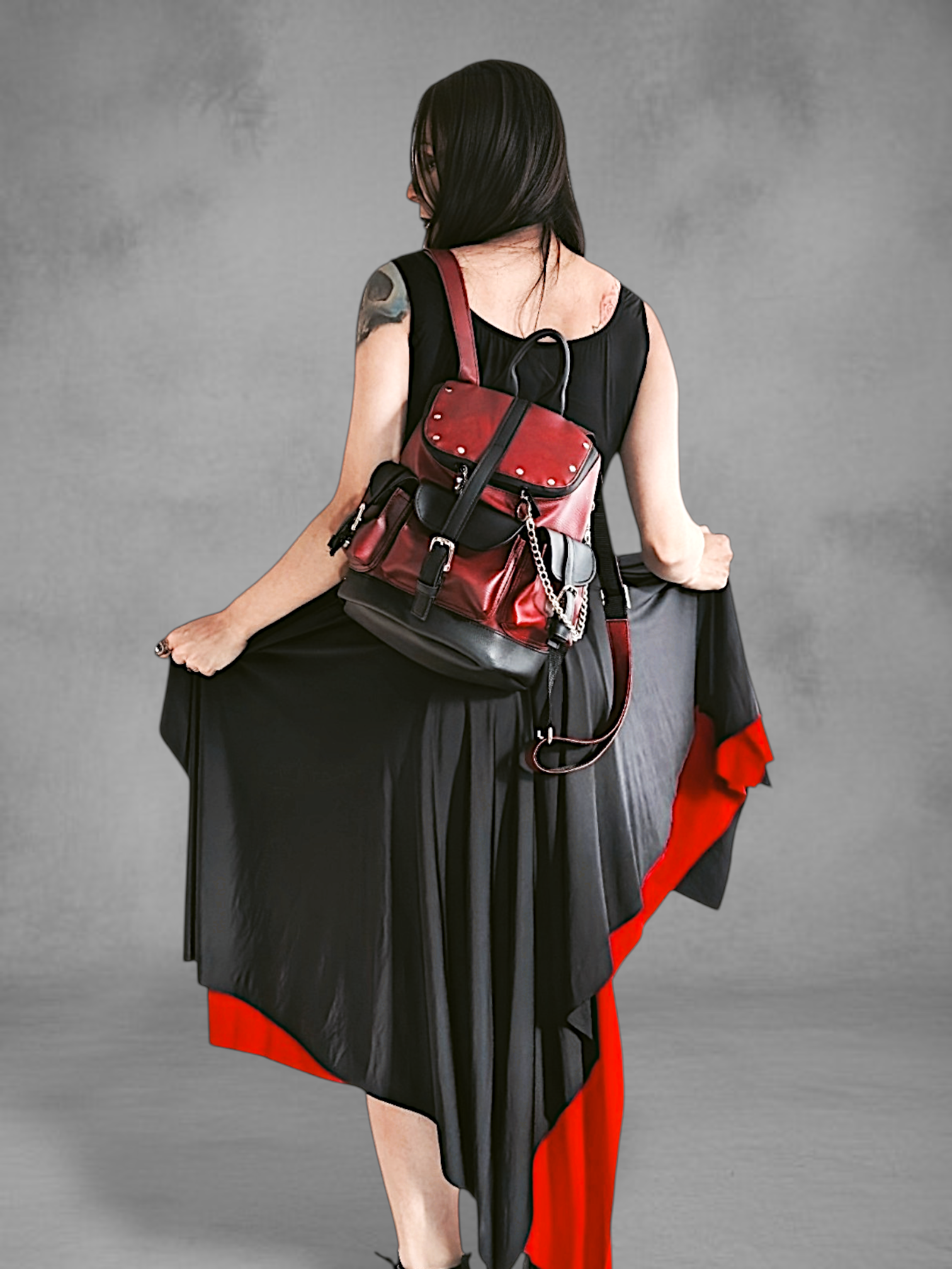 Mochila gotica de cuerina rojo borgona y negro en las manos de una modelo