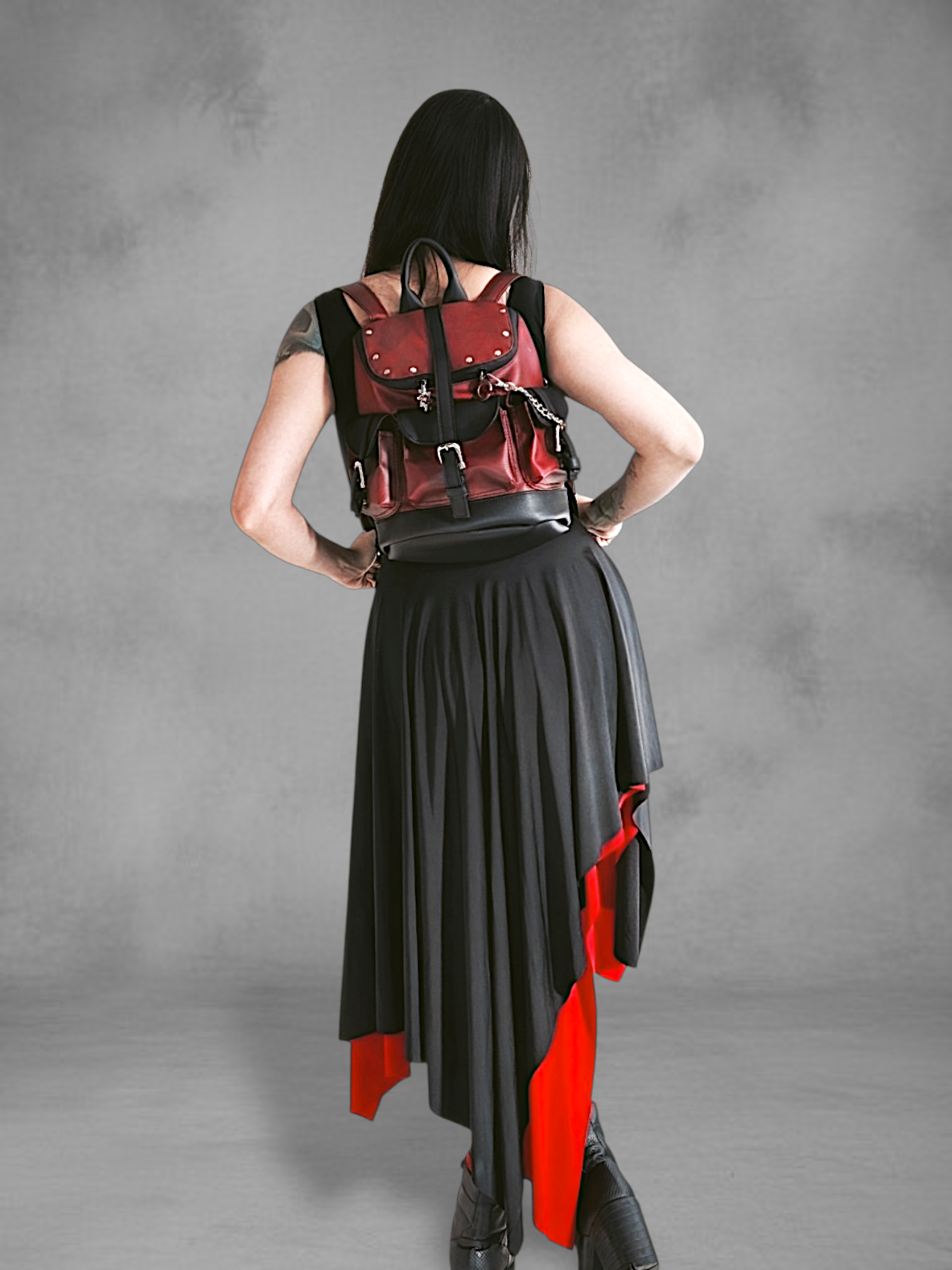 Mochila gotica de cuerina rojo borgona y negro en las manos de una modelo